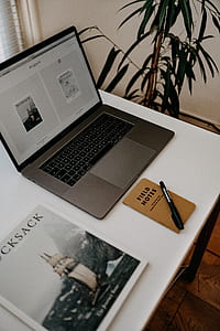 black pen near black and grey laptop on white desk thumbnail
