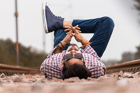 man in sport shirt lying on rail road during day time thumbnail