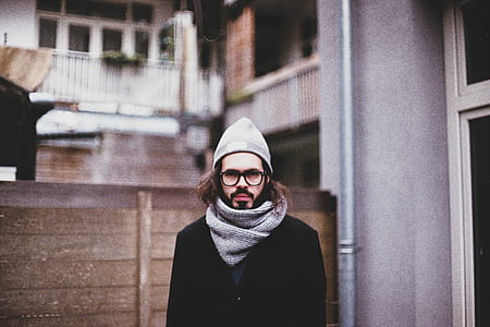 man wearing gray knit cap standing near brown wooden fence looking straight thumbnail