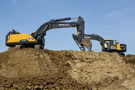 two yellow-and-black Volvo excavators on brown sand under blue sky thumbnail