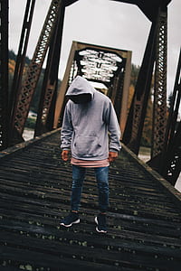 Man in Gray Pull-over Hoodie Standing on Train Rail thumbnail