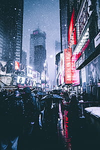 crowd of people walking on street between mountains and high-rise buildings thumbnail