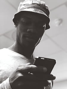 Man in Bucket Hat Holding Black Smartphone thumbnail