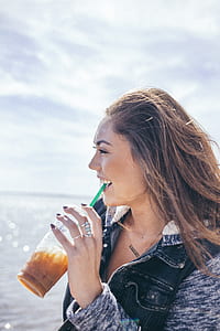smiling woman holding tumbler with green straw on mouth thumbnail