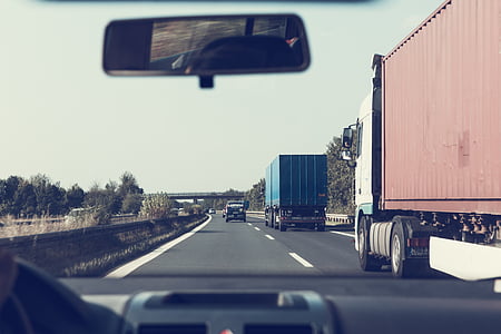person driving in car beside freight truck thumbnail