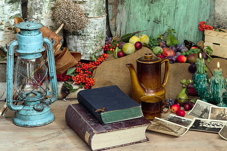 teal tubular lantern beside two books and brown pitcher on table thumbnail