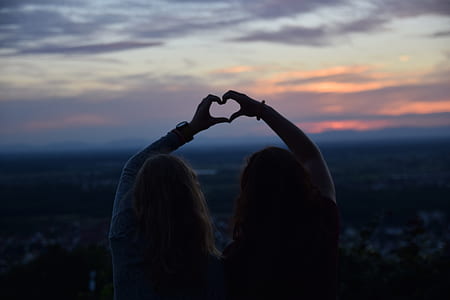 two person forming finger heart during golden hours thumbnail