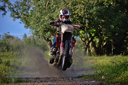 man riding motocross dirt bike near trees thumbnail