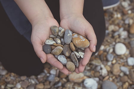person holding gray and brown pebbles thumbnail