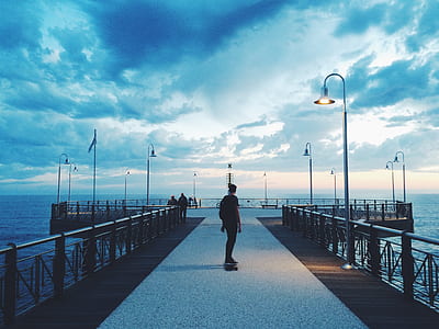 person standing on gray concrete dock during daytime thumbnail