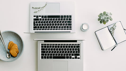two silver laptop computers beside of round gray plate with heart cookies thumbnail