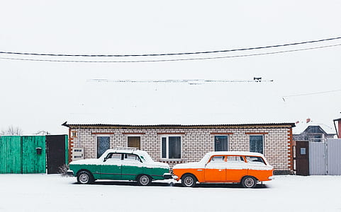 orange and green coupes parked outside brown house with snow thumbnail