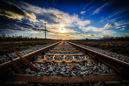 five brown lighted candles on train rail thumbnail