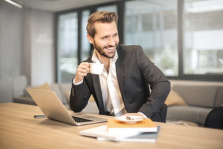 Man Holding White Teacup in Front of Gray Laptop thumbnail