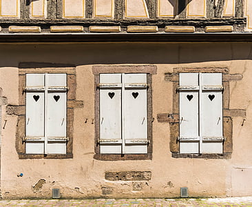 three closed white windows on beige concrete house thumbnail