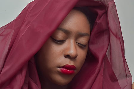 woman closing her eyes with maroon chiffon textile on her head thumbnail