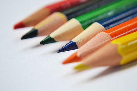 selective focus photography of blue sharpened color pencil between green and orange color pencils on top of white surface thumbnail