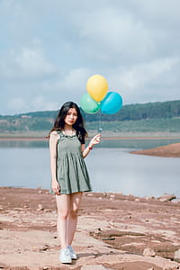 Woman's in Green Sleeveless Dress Holding 3 Balloons thumbnail
