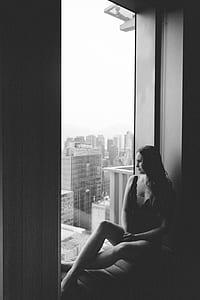woman wearing plunging-neckline shirt sitting on sofa beside glass window thumbnail
