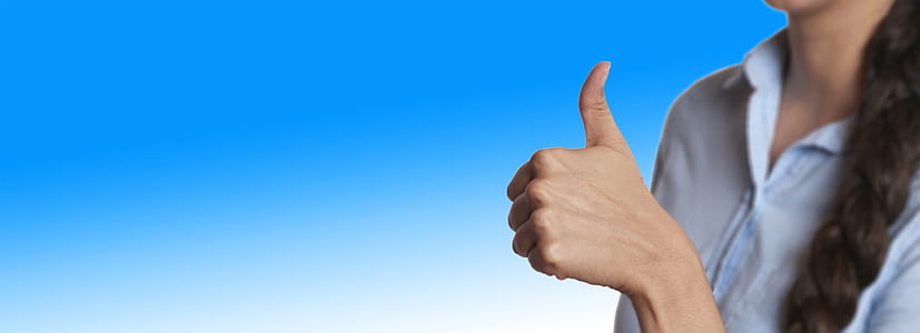 woman wearing blue collared button-up showing thumbs up thumbnail