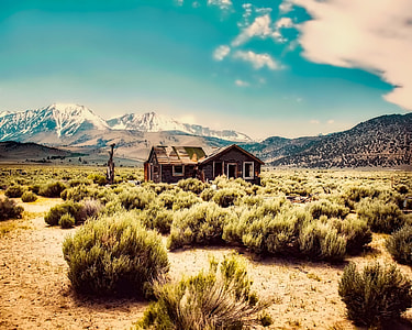 wooden house in the middle of a prairie surrounded with hills thumbnail