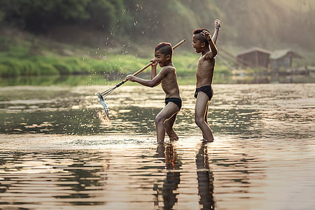 two boys standing on top of water during daytime thumbnail