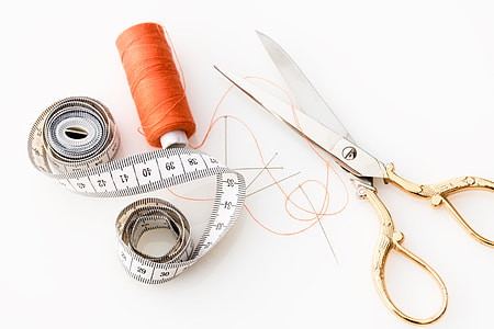 brass and stainless steel scissors beside orange thread thumbnail