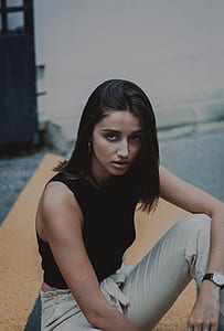 woman in black sleeveless crop top seating on orange surface fashion photography thumbnail
