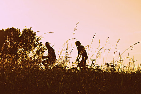 silhouette of man and woman ride on bikes thumbnail