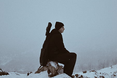 man sitting on log during winter season thumbnail