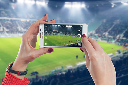 Woman photographer taking photo with mobile smartphone in stadium of soccer match thumbnail