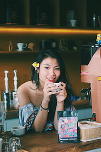 woman sitting beside table white holding cup thumbnail