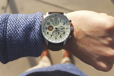 person wearing round silver-colored chronograph watch with brown leather band thumbnail