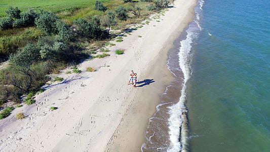 man and woman walking on seashore thumbnail