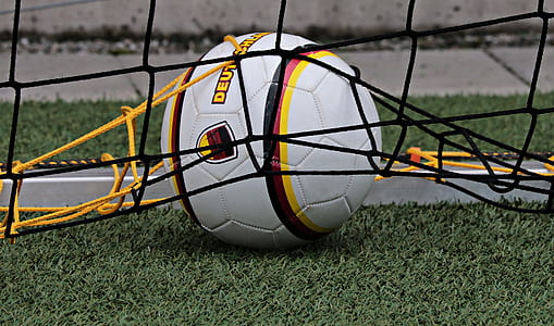 white, yellow, and black soccer ball on green grass thumbnail