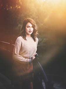 woman wearing brown long-sleeved top beside black steel fence near river thumbnail