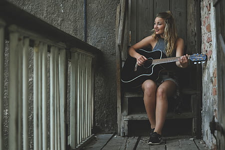 Woman Wearing Gray Tank Top Playing Black Cutaway Acoustic Guitar thumbnail