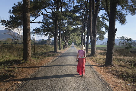 woman walking near trees on road thumbnail