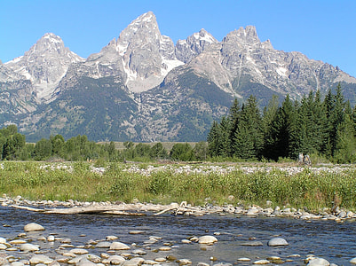 blue body of water in front of trees and mountain thumbnail