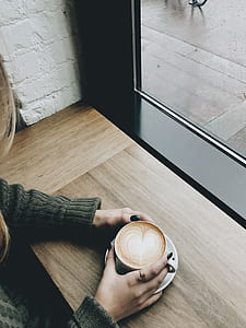 person holding ceramic mug filled with coffee using both hands thumbnail