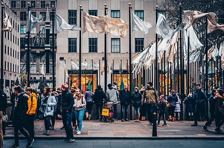 people on pathway beside road and building with flags during daytime thumbnail