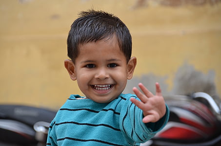 boy wearing blue and black striped sweater reaching and smiling selective-focus photography thumbnail