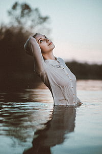 woman in white dress shirt while swimming during daytime thumbnail