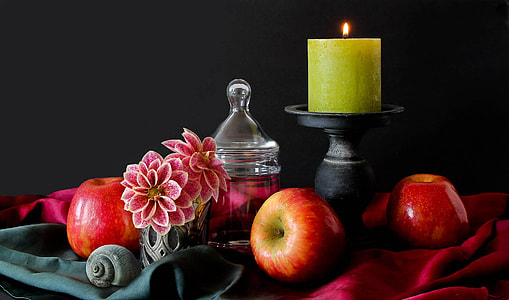 apple beside of black wooden candle holder with green votive candle on top table thumbnail