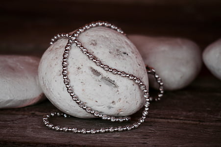 silver-colored necklace on white polished pebble thumbnail