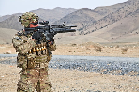 military man holding rifle in an open field thumbnail