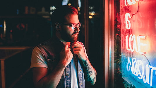 man standing near neon light signage on wall inside room thumbnail