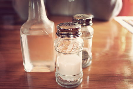 two clear glass condiment shakers on table thumbnail