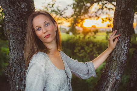 woman leaning on grey tree trunk outdoors thumbnail