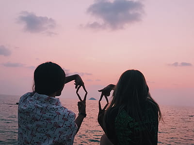 Two Woman Sitting in Front of Body of Water thumbnail